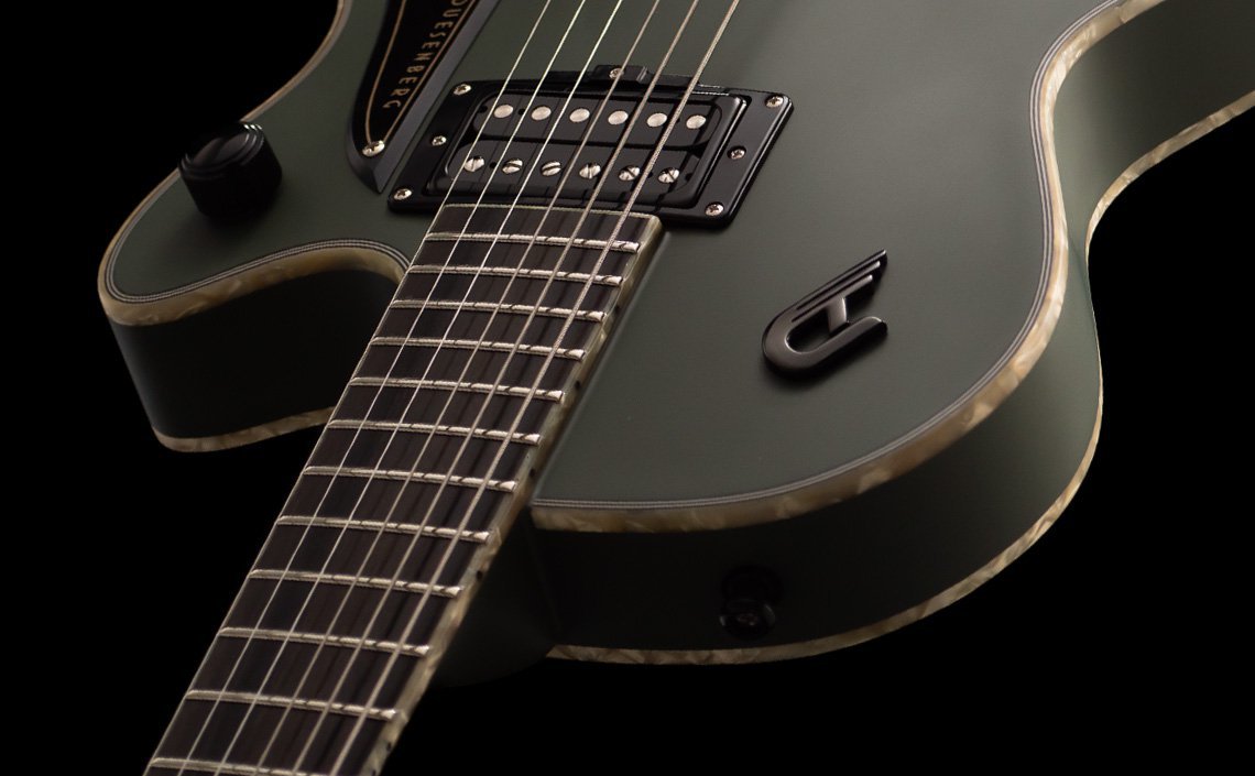 "Close-up of a Duesenberg electric guitar in a matte olive finish with a glossy texture and light-colored binding around the edges. The image highlights the black pickup with silver screws, the metallic strings, and the stylized 'D' logo, showcasing the guitar's detailed craftsmanship and premium design.