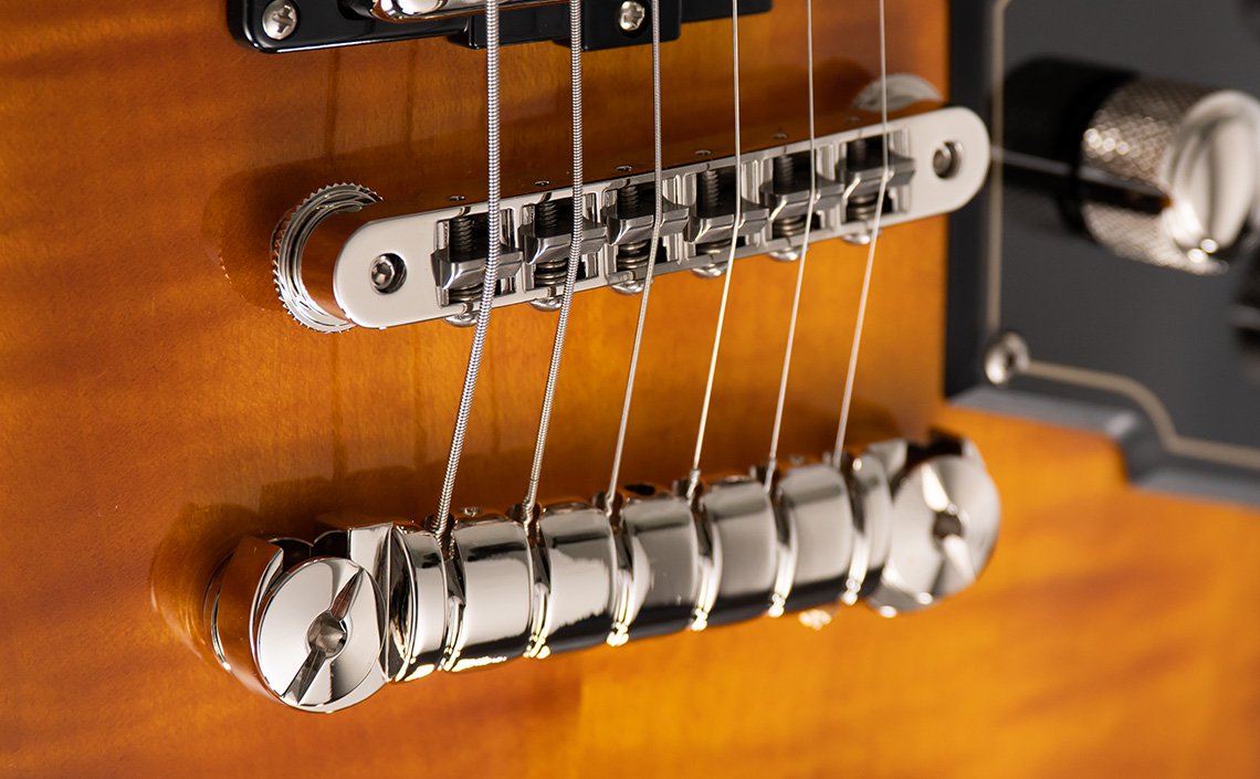 "Close-up of the Duesenberg electric guitar bridge, showcasing the sleek chrome hardware against a glossy sunburst finish. The iconic Duesenberg logo stands out, highlighting the brand's signature style and precision craftsmanship.