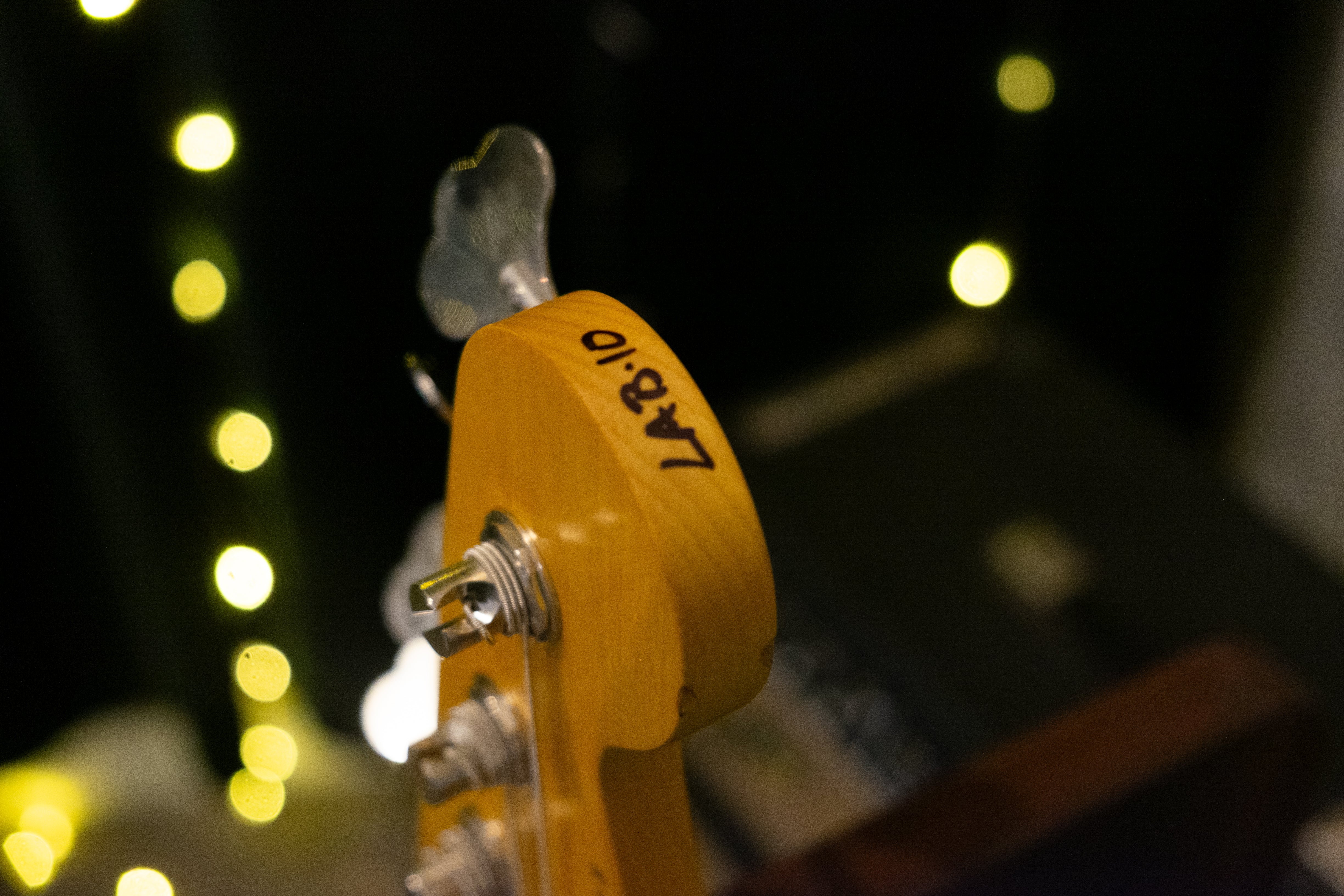 Nash PB63 bass headstock with 'LAB.10' handwritten, featuring classic tuners and vintage wear