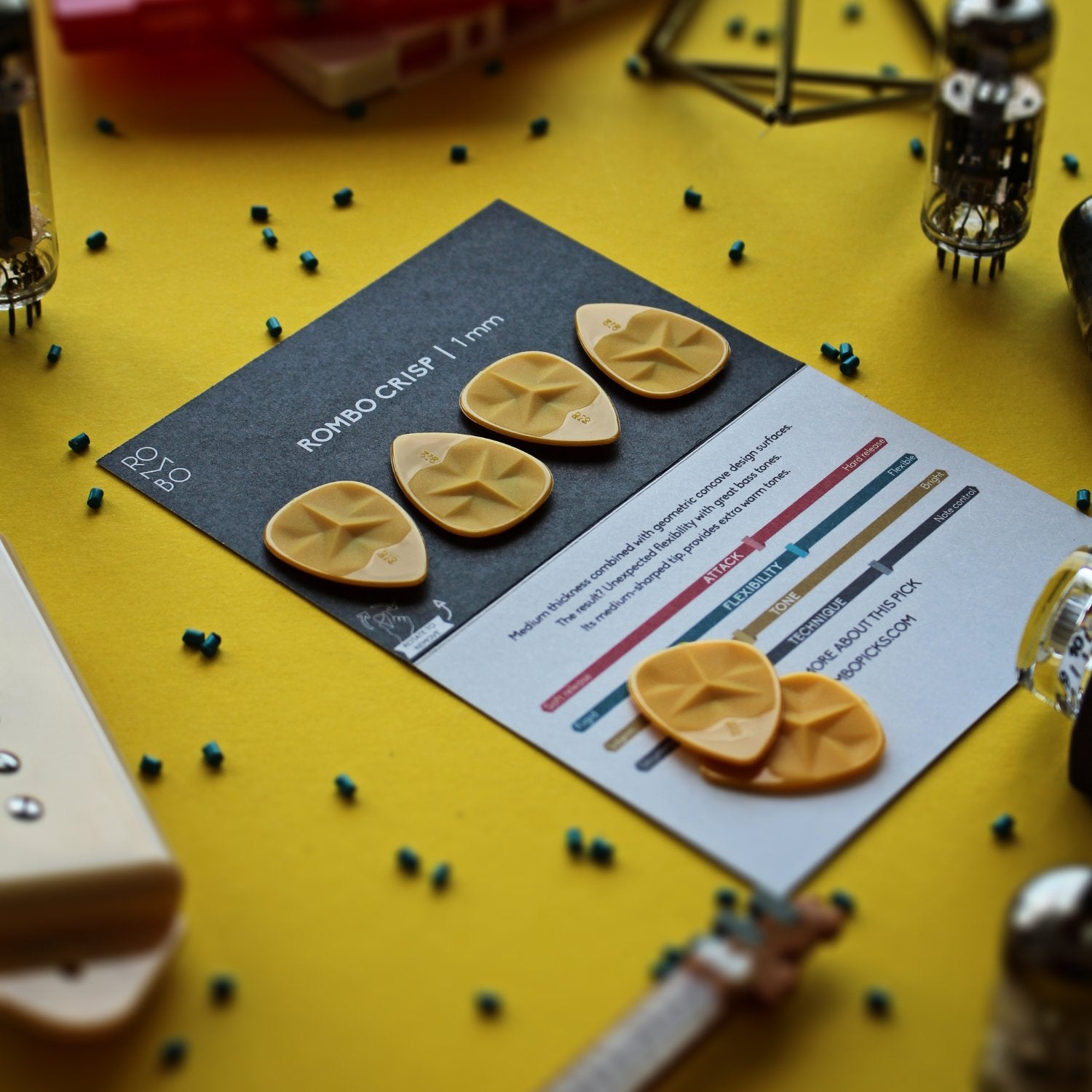 Black card with text and graphics on a yellow background, surrounded by guitar picks