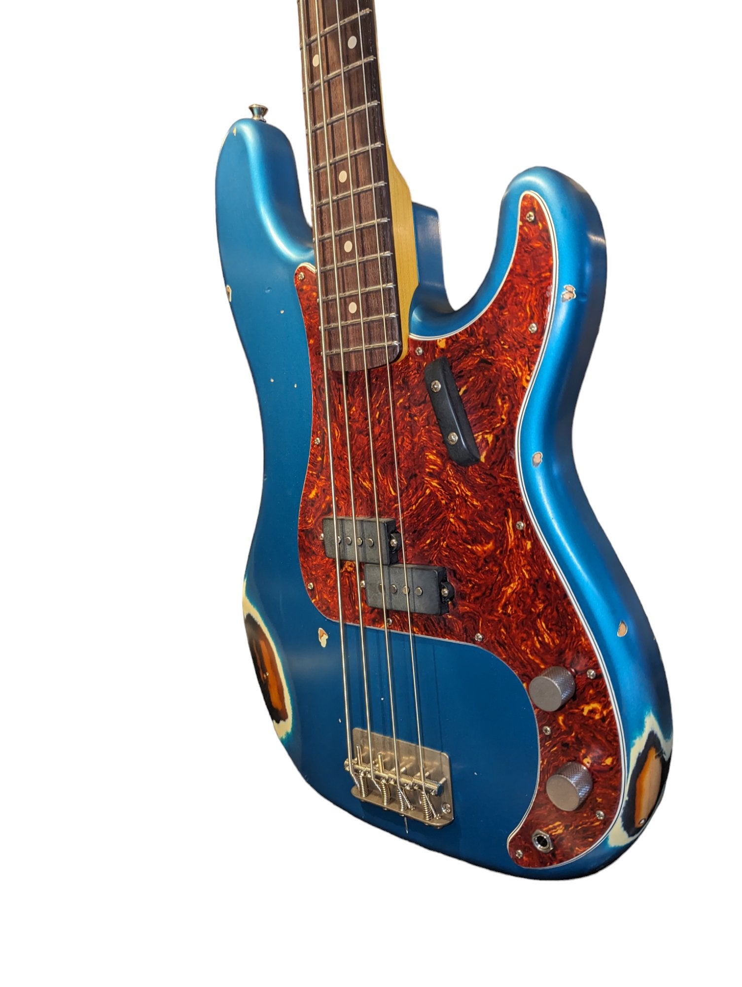 Close-up of a Nash electric bass guitar with a worn blue body and a reddish-brown marbled tortoiseshell pickguard.