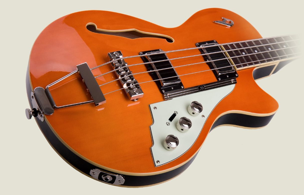 Orange semi-hollow electric guitar with f-hole, trapeze tailpiece, three pickups, chrome hardware, and glossy finish.